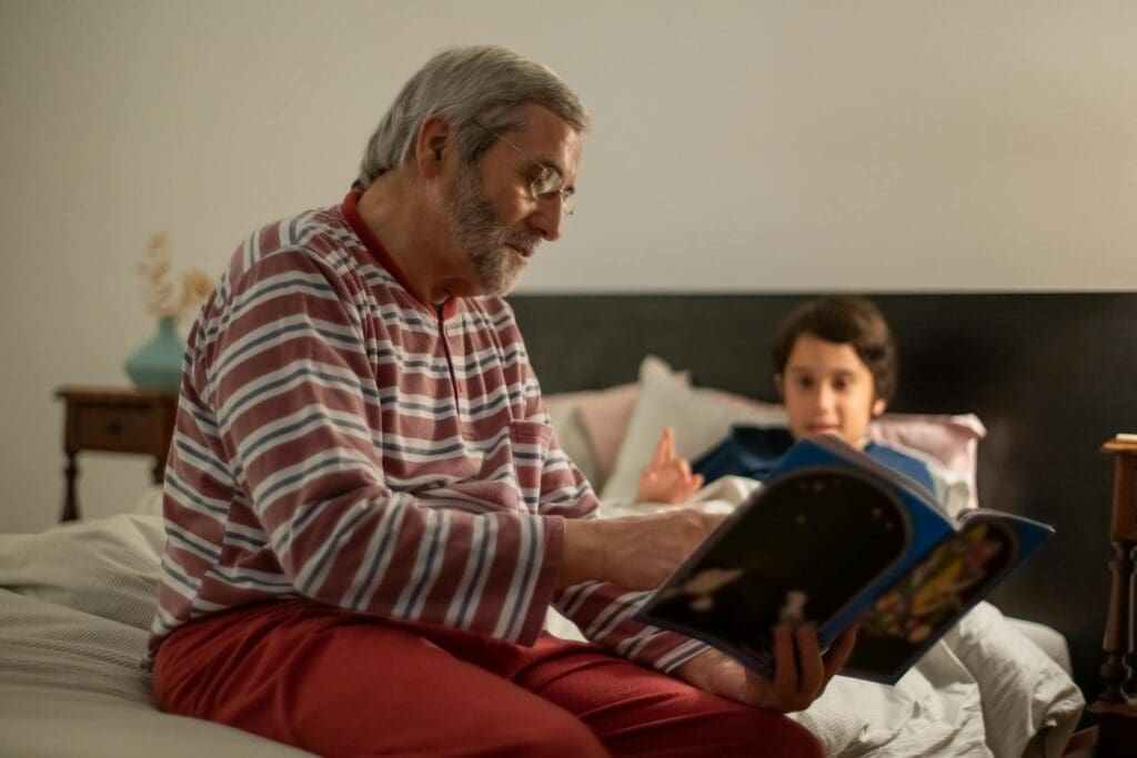 An older man reading to his grandson. With Help at Home expertise, we understand  the impact of nutrition on cognitive health has never been more critical, especially in the context of dementia care in Reno-Sparks.